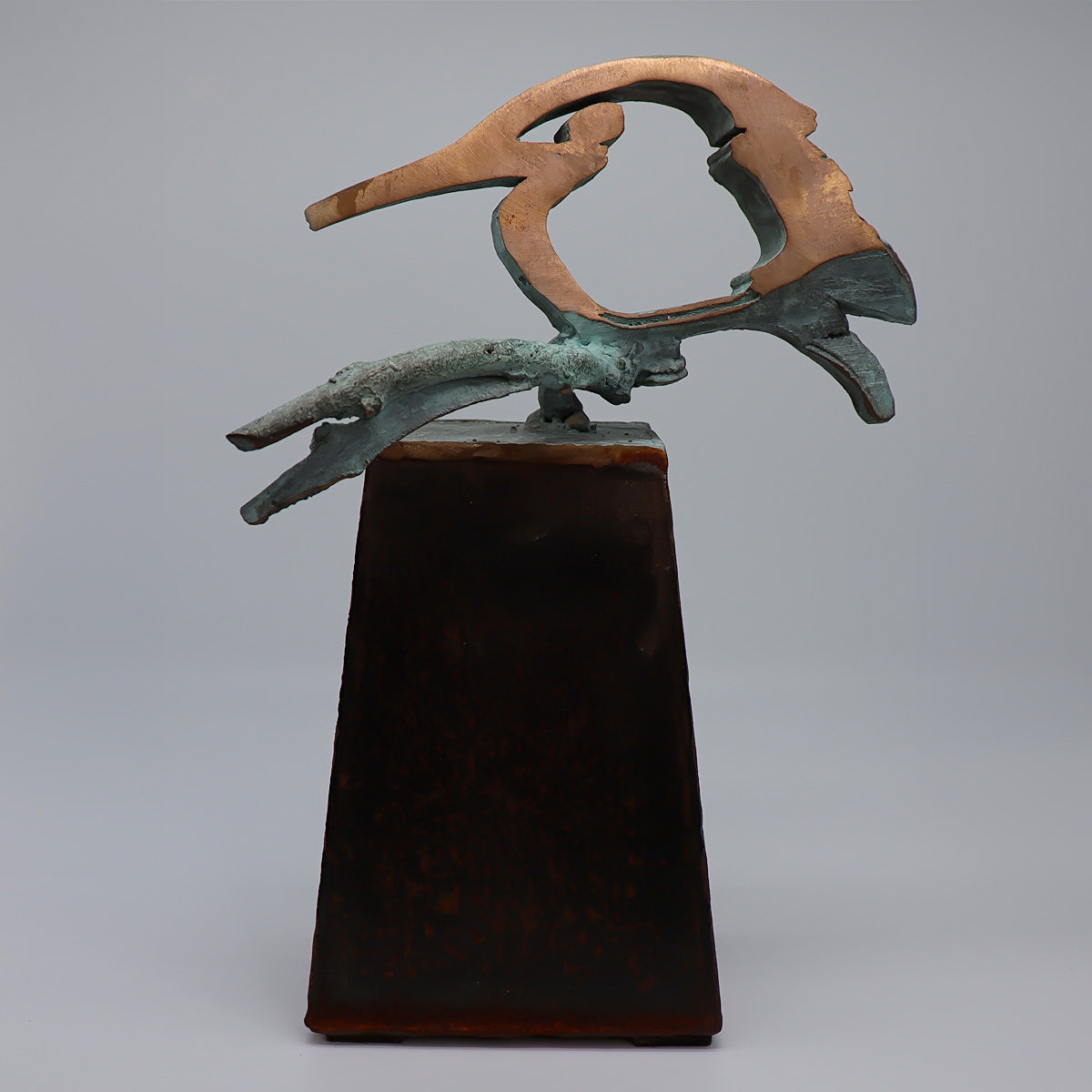 Elegante midi urn van JEART met bronzen ijsvogel vrede op een tak, geplaatst op een cortensokkel. Duurzame materialen symboliseren kracht en eeuwigheid, terwijl de ijsvogel staat voor hoop en nieuwe beginnen. Een stijlvolle en betekenisvolle herinnering.