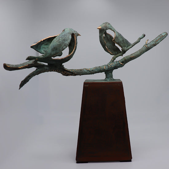 Midi urn van JEART met twee bronzen vogels op een tak, symboliserend verbondenheid en samenzijn. Geplaatst op een cortenstalen sokkel, biedt het een stijlvolle herdenkingsplek waarbij de vogels staan voor liefde en eeuwige samenhorigheid.